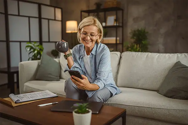 Woman using her phone while enjoying a hot beverage.