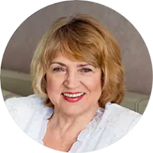 A portrait image of an older woman wearing a white blouse, smiling.